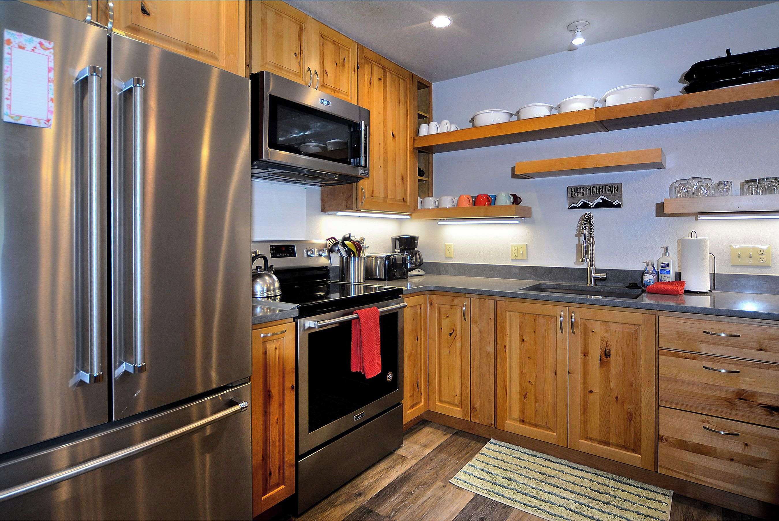 A modern kitchen with stainless steel appliances, wooden cabinets, and a built-in microwave.