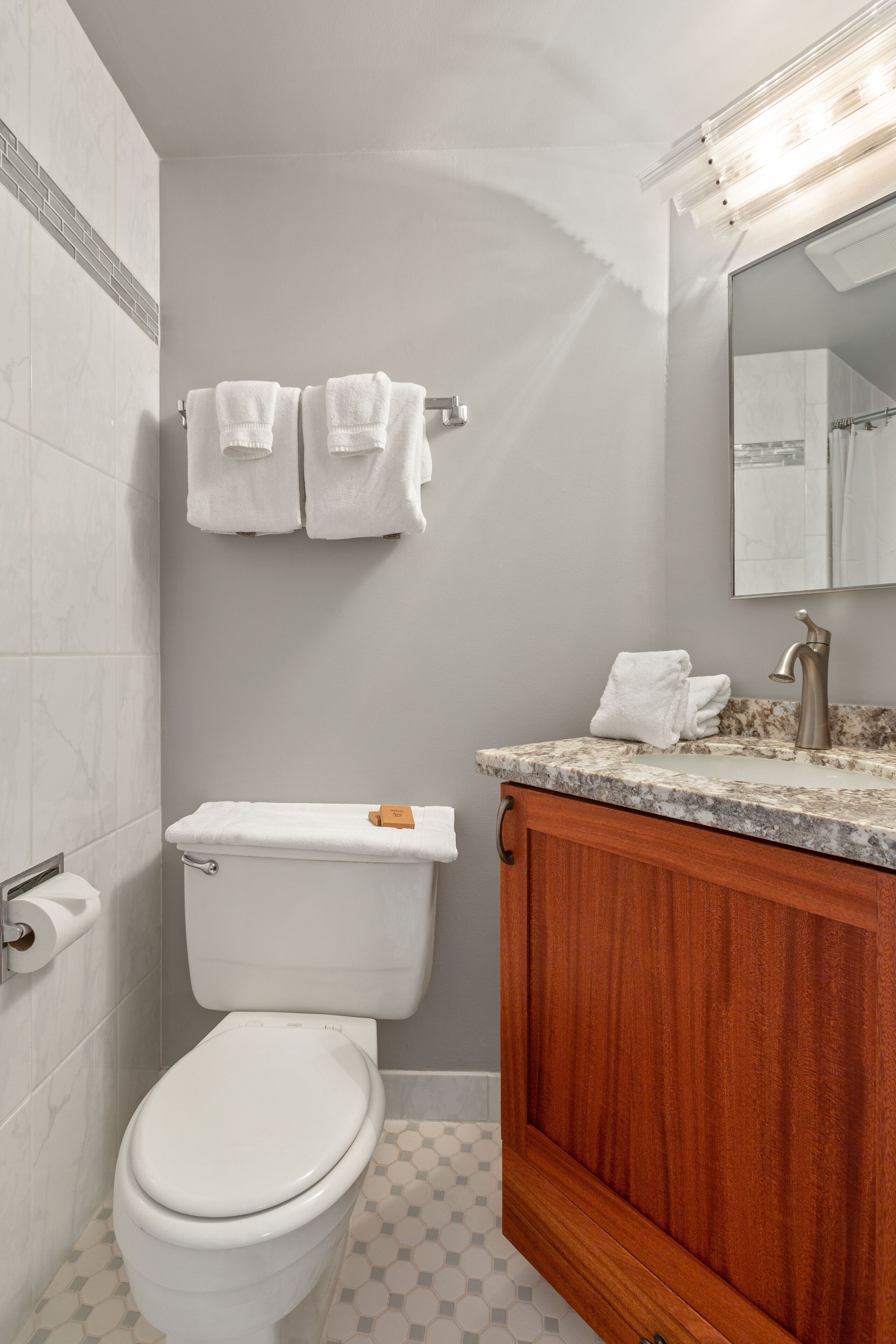 A bathroom with a toilet, a sink with a mirror, and a towel rack.