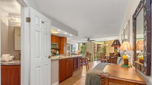 A spacious kitchen with wooden cabinets, a central island, and a dining area with a table and chairs. - Popular location at ocean front condo resort (Kihei)