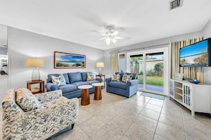 Relax in this stylish living room with a large window offering a view of the outdoors, a flat-screen TV, and comfortable seating for two.