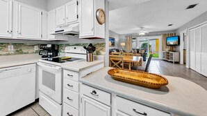 Une cuisine moderne avec des meubles blancs, une cuisinière et un coin repas comprenant une table et des chaises.