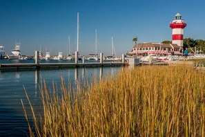 A marina with boats docked, a lighthouse, and a building with a red and white striped awning. - Racquet Club Villas 2321- Charming Sea Pines 1 bedroom plus Bonus Loft!! (Hilton Head Island)