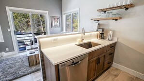 Una cocina moderna con lavavajillas, cafetera y estante de madera con tazas.