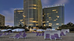 A hotel with multiple high-rise buildings, beachside lounge chairs, and umbrellas. - Most Luxury hotel 5 stars oceanfront w. balconies - Valet & Amenities included (Bal Harbour)