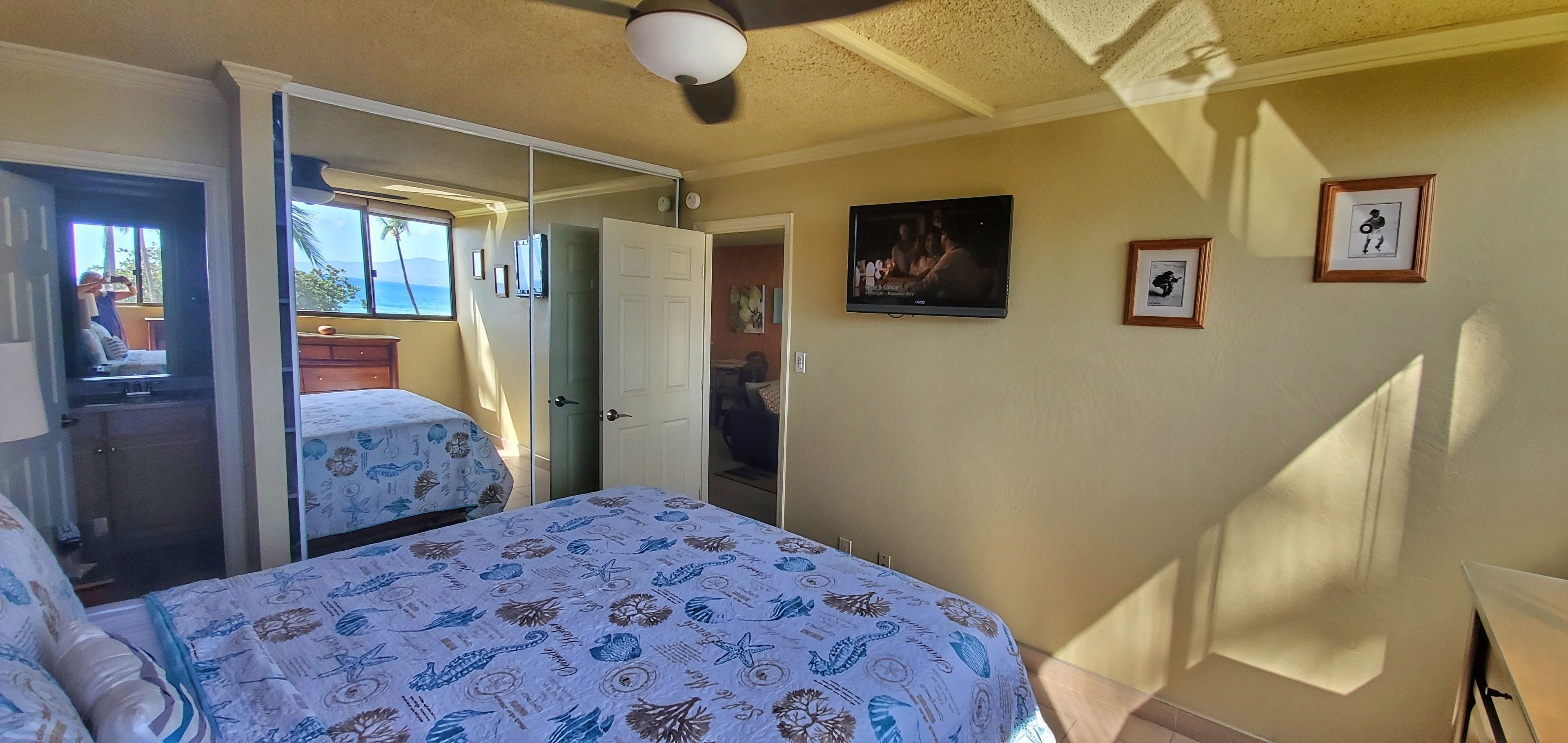 A bedroom with a bed, a wardrobe, and a television on the wall.
