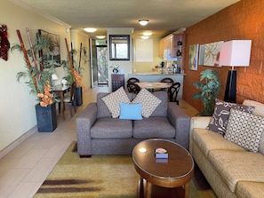 A living room with a grey sofa, a round coffee table, and a dining area with a table and chairs.