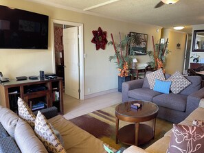 A living room with a sofa, a coffee table, a TV, and a bookshelf.