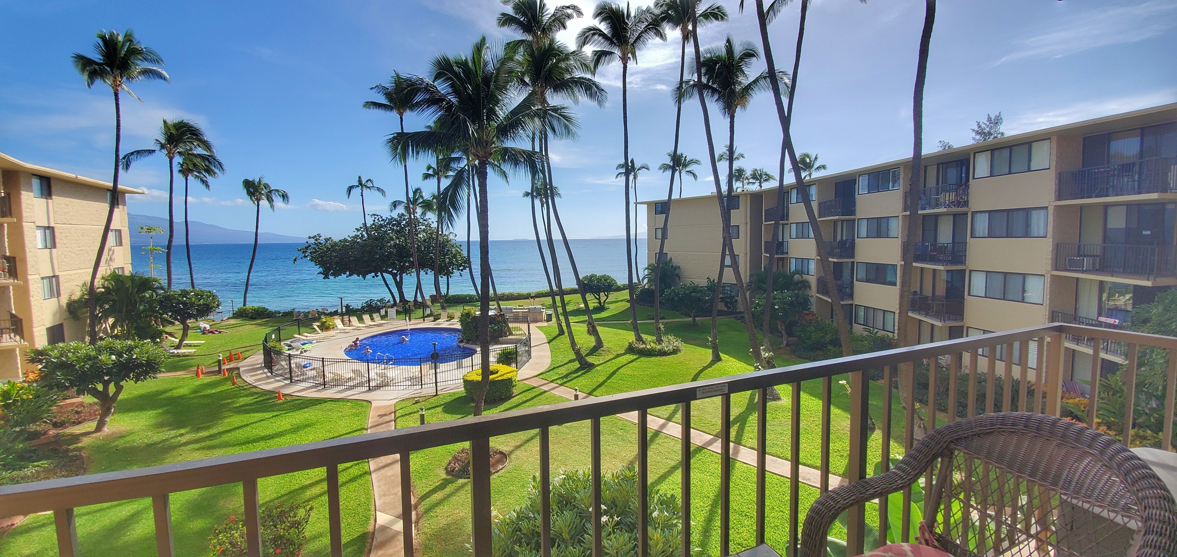 A hotel with a pool surrounded by palm trees and a view of the ocean.