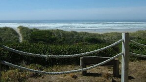 A coastal view with a rope barrier and a bench, overlooking the ocean.