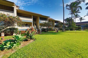 A hotel with a two-story structure, a covered walkway, and a well-maintained lawn.