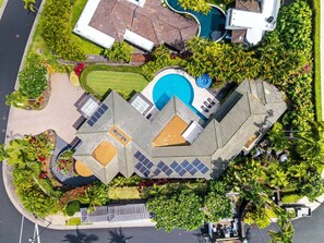 Una propiedad residencial con piscina, paneles solares y jardín ajardinado.