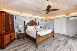 Un dormitorio con una cama de madera, dos mesitas de noche con lámparas, un ventilador de techo y un armario.