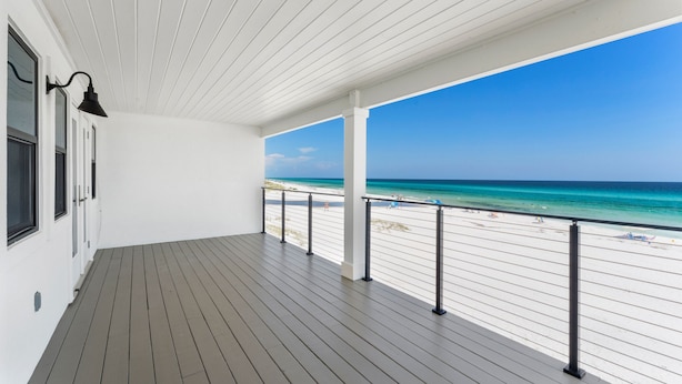 Un balcon fermé offrant une vue sur une plage et l’océan.