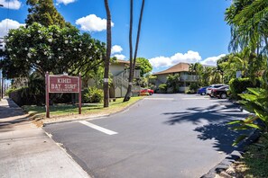 A street view with a sign for 'KIHEI BAY SURF' and a building with a balcony.