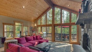 A spacious living room with a large red sectional sofa, a wooden coffee table, and a stone fireplace. - The Lodge at Swiss Lane - TLUXP (Truckee)