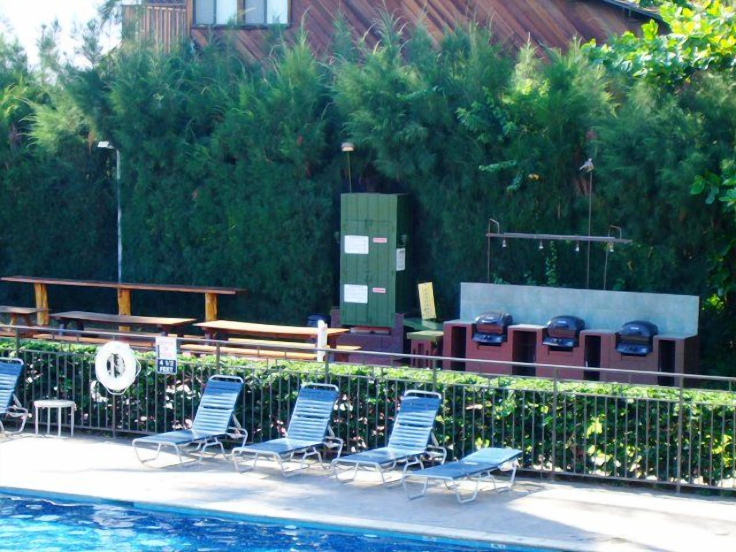 A pool area with lounge chairs and a wooden deck.