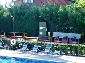 A pool area with lounge chairs and a wooden deck.
