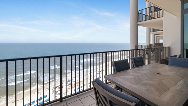 A balcony with a view of the beach and ocean, a table with chairs, and a railing. - The Oasis At Orange Beach 1910 by Liquid Life (Orange Beach)
