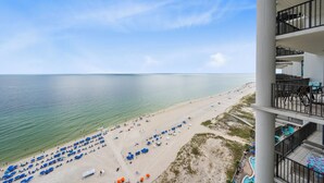 A beach view from a hotel balcony with multiple levels, outdoor seating, and a pool area. - The Oasis At Orange Beach 1910 by Liquid Life (Orange Beach)