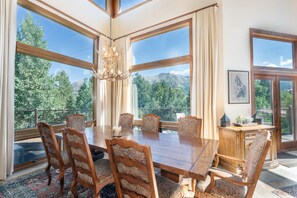 Une salle à manger avec une grande table en bois, des chaises à motifs et un lustre.