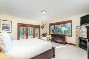 Une chambre spacieuse avec un grand lit, une cheminée en pierre et une tête de cerf accrochée au mur.