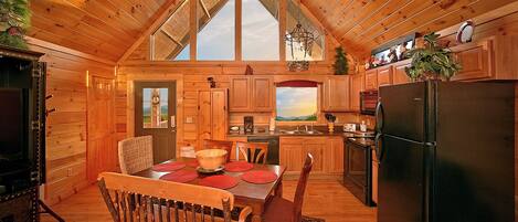 A cozy cabin with a dining area, kitchen, and a large window.