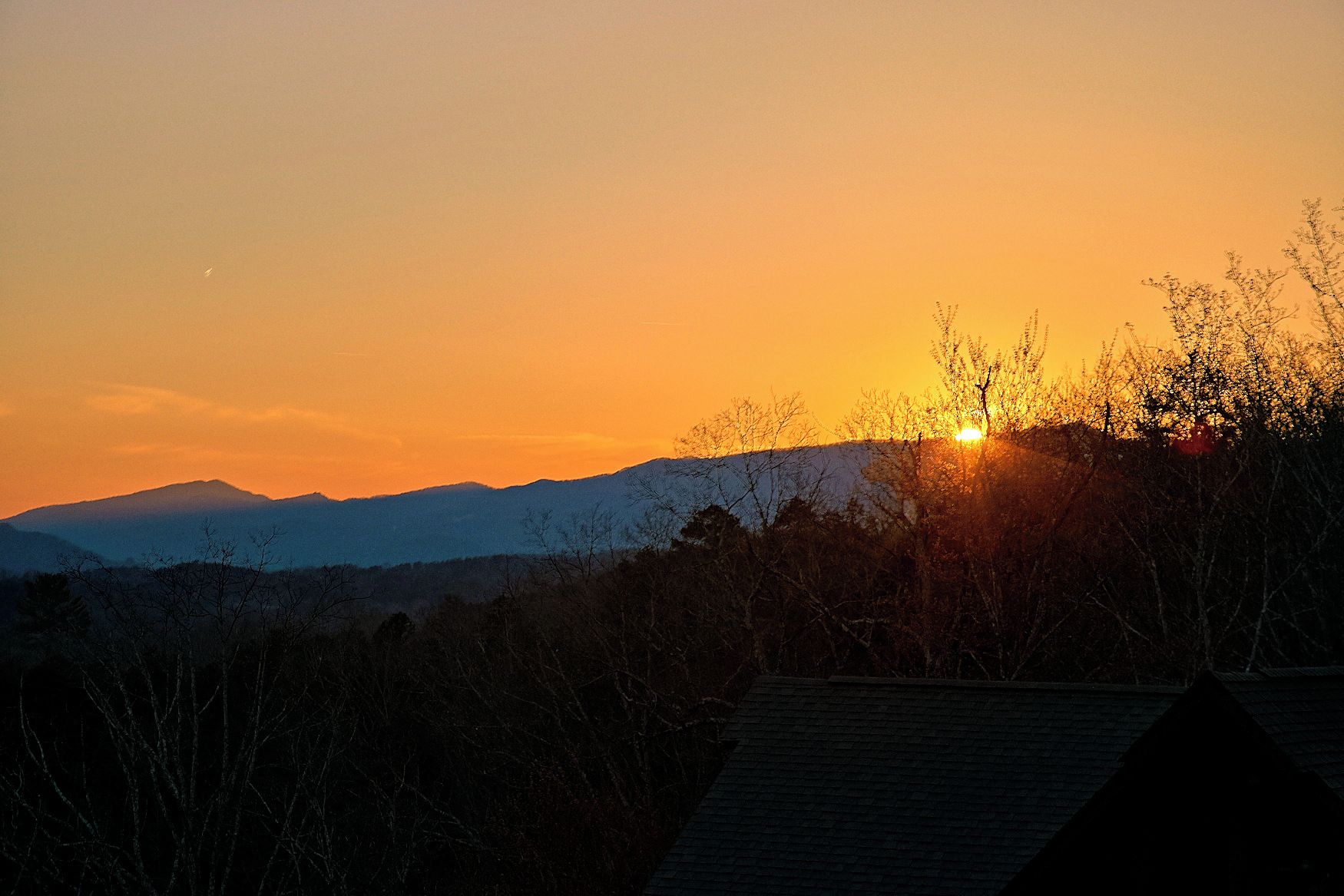 A sunset over a mountainous landscape with a clear sky.