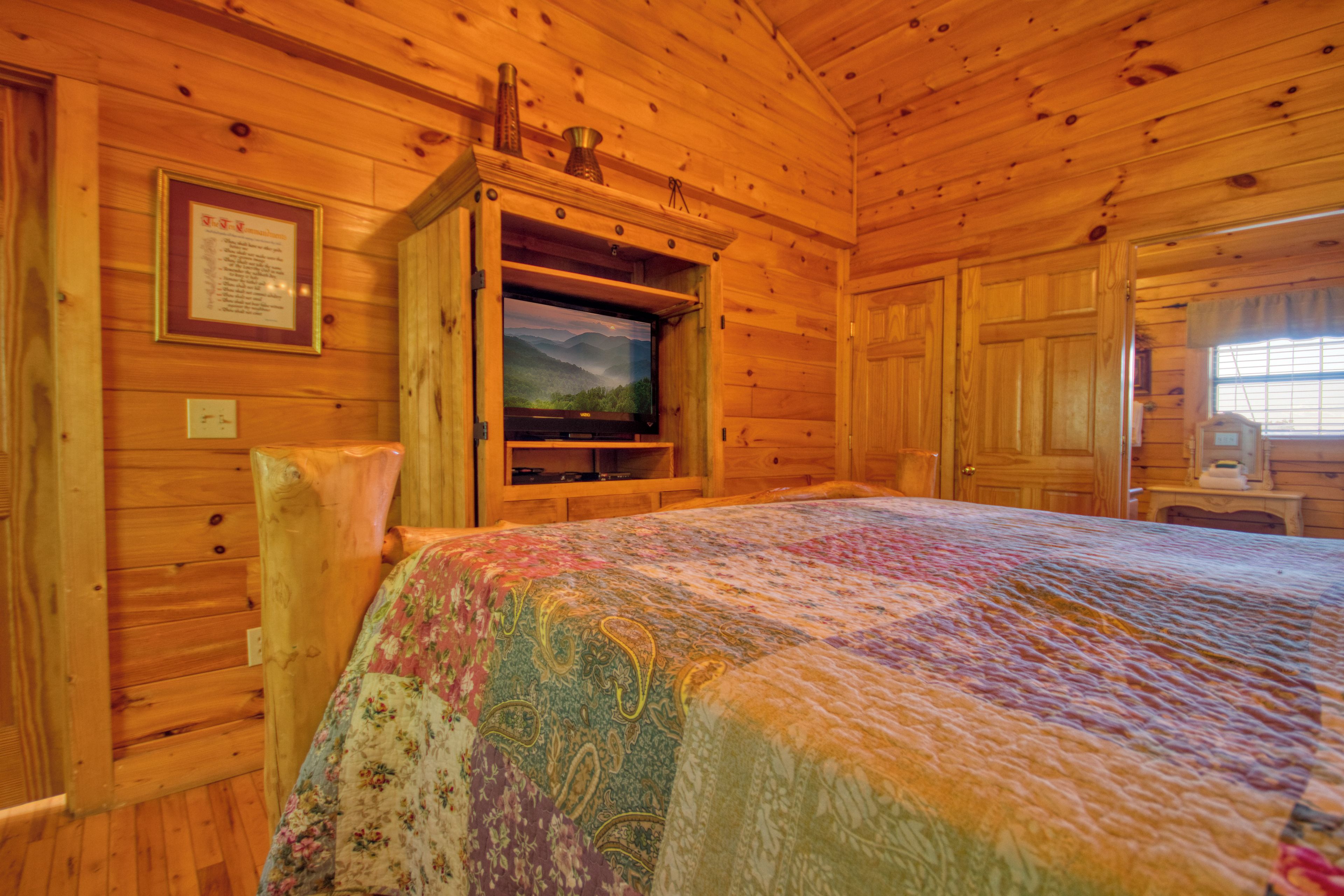 Une chambre rustique en bois, avec un lit, un téléviseur fixé au mur et un avis encadré accroché au mur.