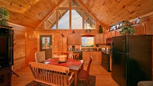 A cozy cabin with a dining area, kitchen, and a large window. - View of Dollywood’s Fireworks|Pool Table|Hot Tub (SEVIERVILLE)