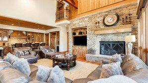 A spacious living room with leather sofas, a stone fireplace, and a large television. - Pristine Mountain Home. Perfect for Families - Hot Tub, Media Room & Elevator (Park City)