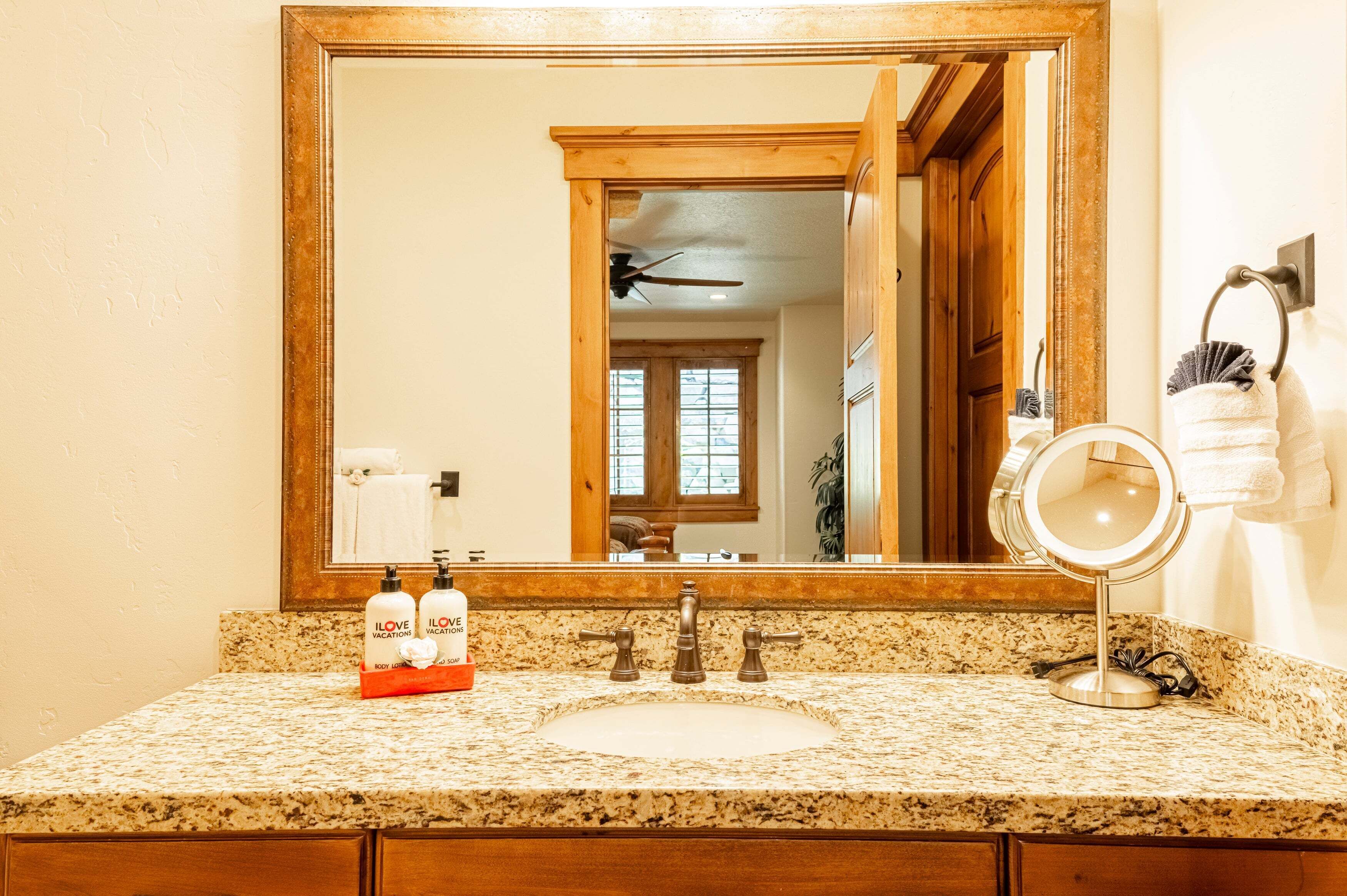 Une salle de bain avec un comptoir en granit, un lavabo, un miroir et un meuble-lavabo doté d’un porte-serviettes.