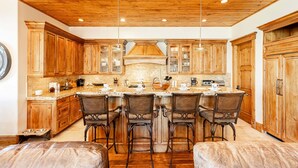 A kitchen with wooden cabinets, a central island with bar stools, and pendant lighting. - Pristine Mountain Home. Perfect for Families - Hot Tub, Media Room & Elevator (Park City)