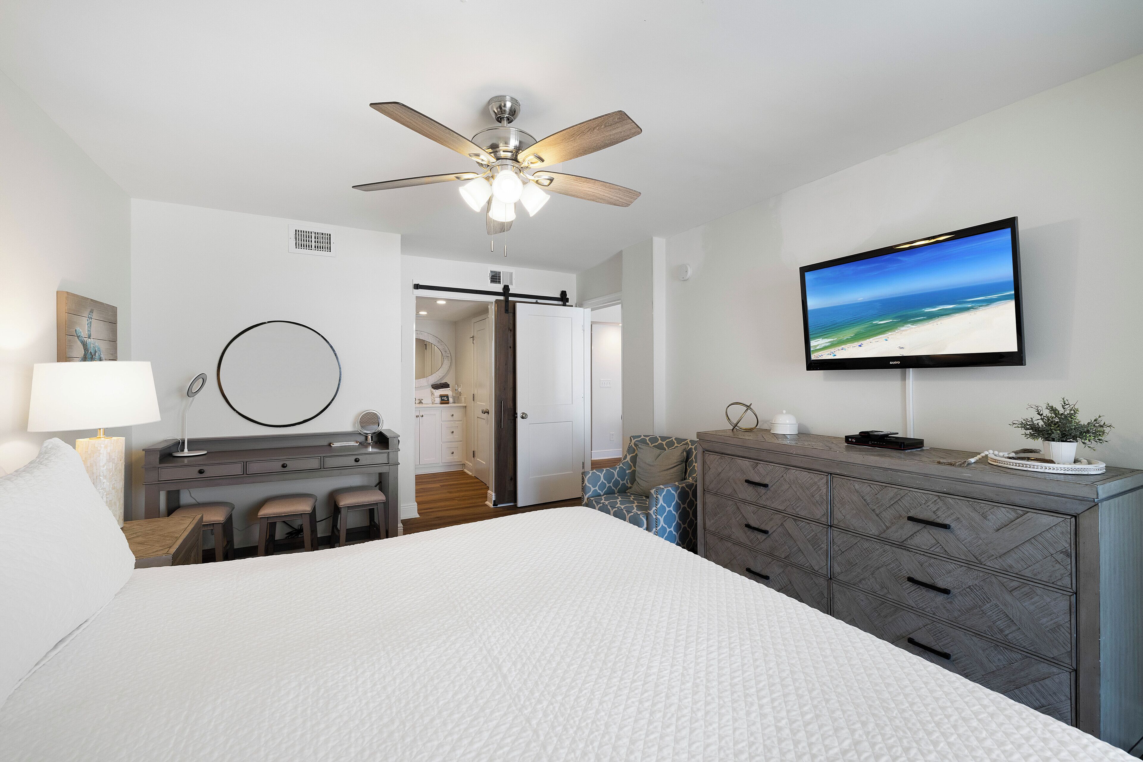 A hotel room with a bed, a desk, a TV, and a ceiling fan.