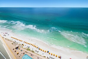 A beach with a pool and umbrellas.