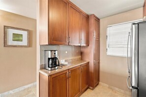 Una cocina con alacenas de madera, un refrigerador de acero inoxidable y una cafetera sobre la encimera.