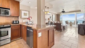A modern kitchen with wooden cabinets, stainless steel appliances, and a large island. - Your Refreshing Escape by the Ocean! Marvelous Views - Royal Mauian 209 (Kihei, Maui)