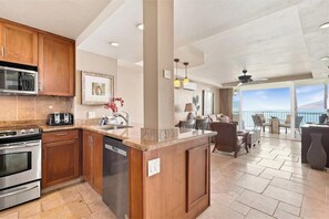 A modern kitchen with wooden cabinets, stainless steel appliances, and a large island. - Your Refreshing Escape by the Ocean! Marvelous Views - Royal Mauian 209 (Kihei, Maui)
