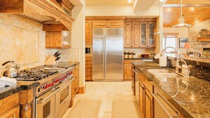A kitchen with wooden cabinets, a stainless steel refrigerator, a gas stove, and granite countertops. - Modern Mountain Design, High-End Kitchen, Theater Room & Hot Tub! (Park City)