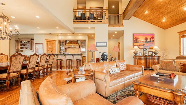 A spacious living area with leather sofas, a dining table, and a kitchen in the background. - Modern Mountain Design, High-End Kitchen, Theater Room & Hot Tub! (Park City)