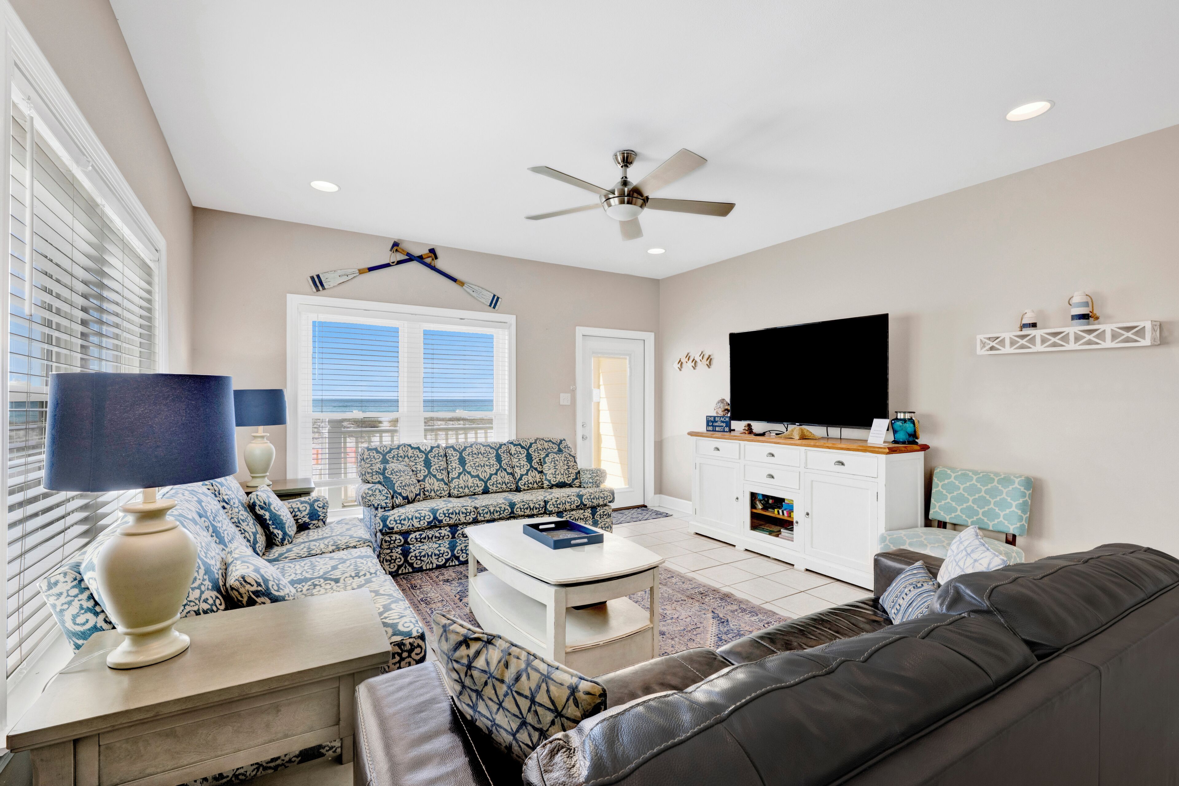 A living room with a sofa, coffee table, TV, and ceiling fan.