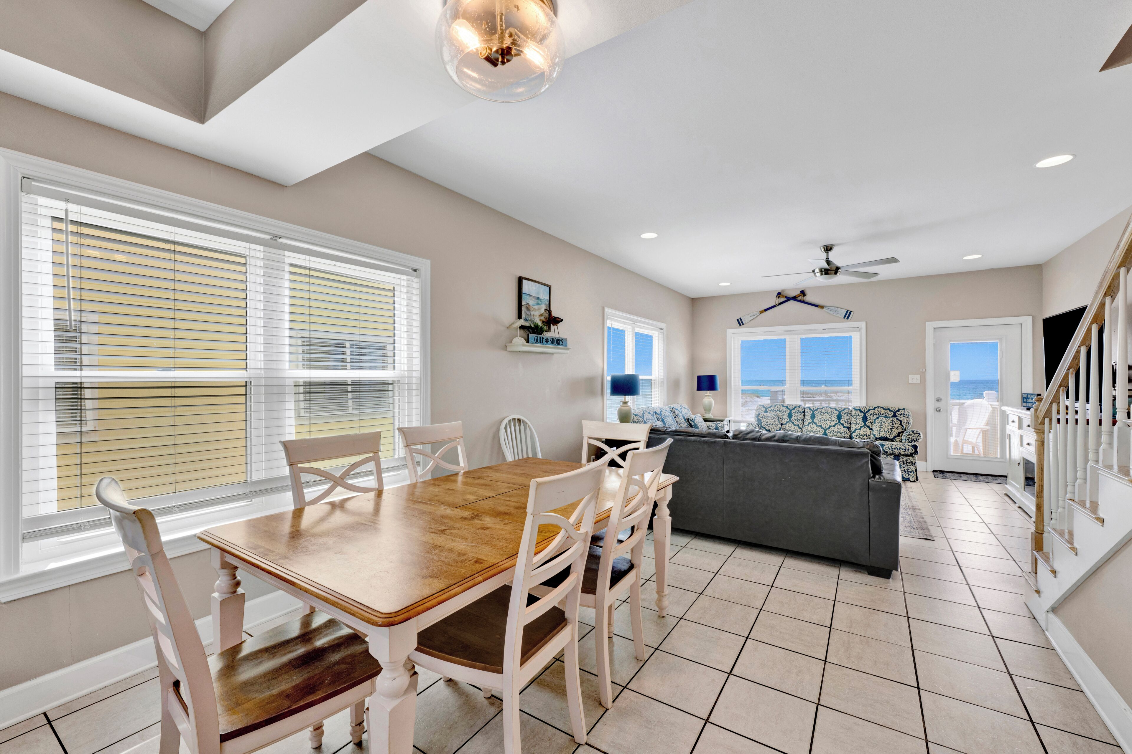 A spacious living area with a dining table, chairs, a sofa, and a staircase.
