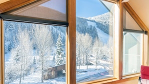 Ein Zimmer mit großen Fenstern und Blick auf eine verschneite Landschaft mit Bäumen und einem Gebäude.