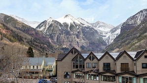 Eine Berglodge mit mehreren Gebäuden, einem Parkplatz und Blick auf schneebedeckte Berge.