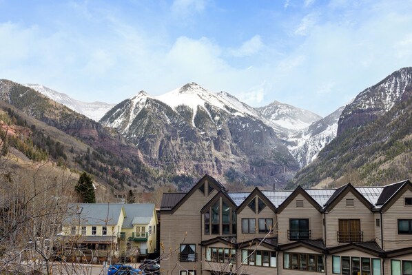 A mountain lodge with multiple buildings, a parking area, and a view of snow-capped mountains.