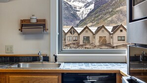 Eine Küche mit Geschirrspüler von Bosch, Holzschränken, einer eingebauten Spüle und einem Fenster mit Blick auf eine Berglandschaft.
