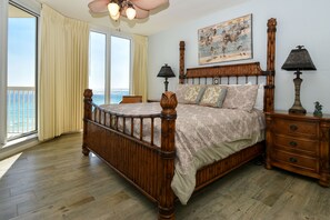 A bedroom with a wooden bed, two bedside tables, a large window with curtains, and a painting on the wall. - Nautical-themed beachfront getaway w/private balcony! 🌊 (Destin)