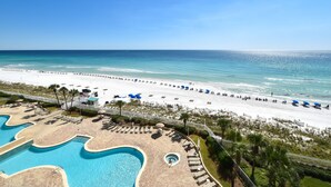 A resort with a large pool area, a beach with umbrellas and lounge chairs, and a clear view of the ocean. - Nautical-themed beachfront getaway w/private balcony! 🌊 (Destin)