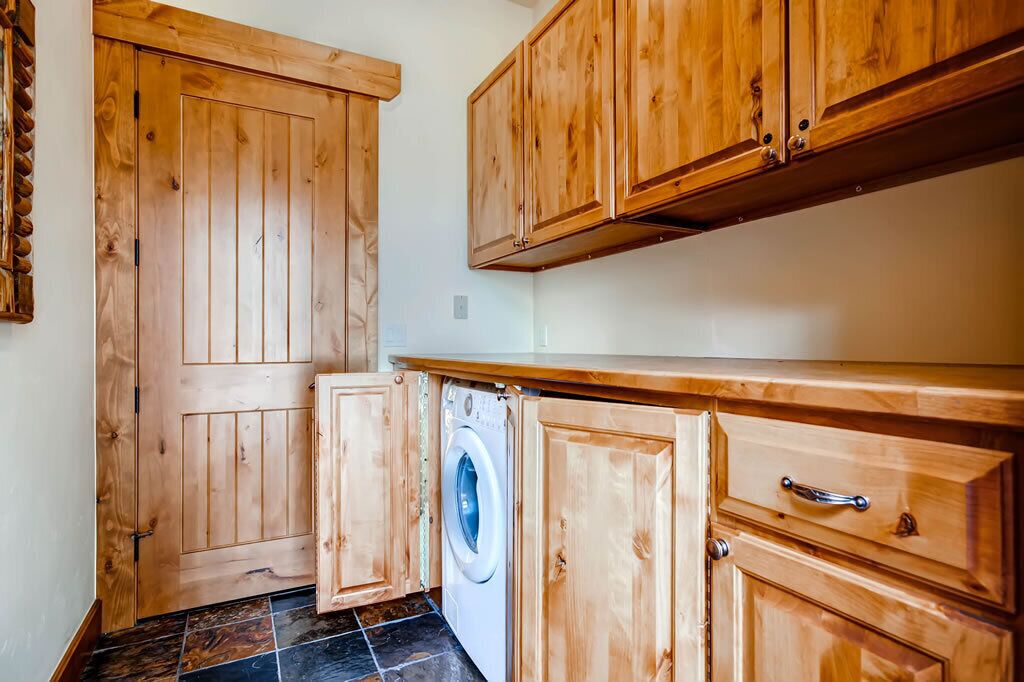 A compact kitchen with wooden cabinets, a washing machine, and a tiled floor.