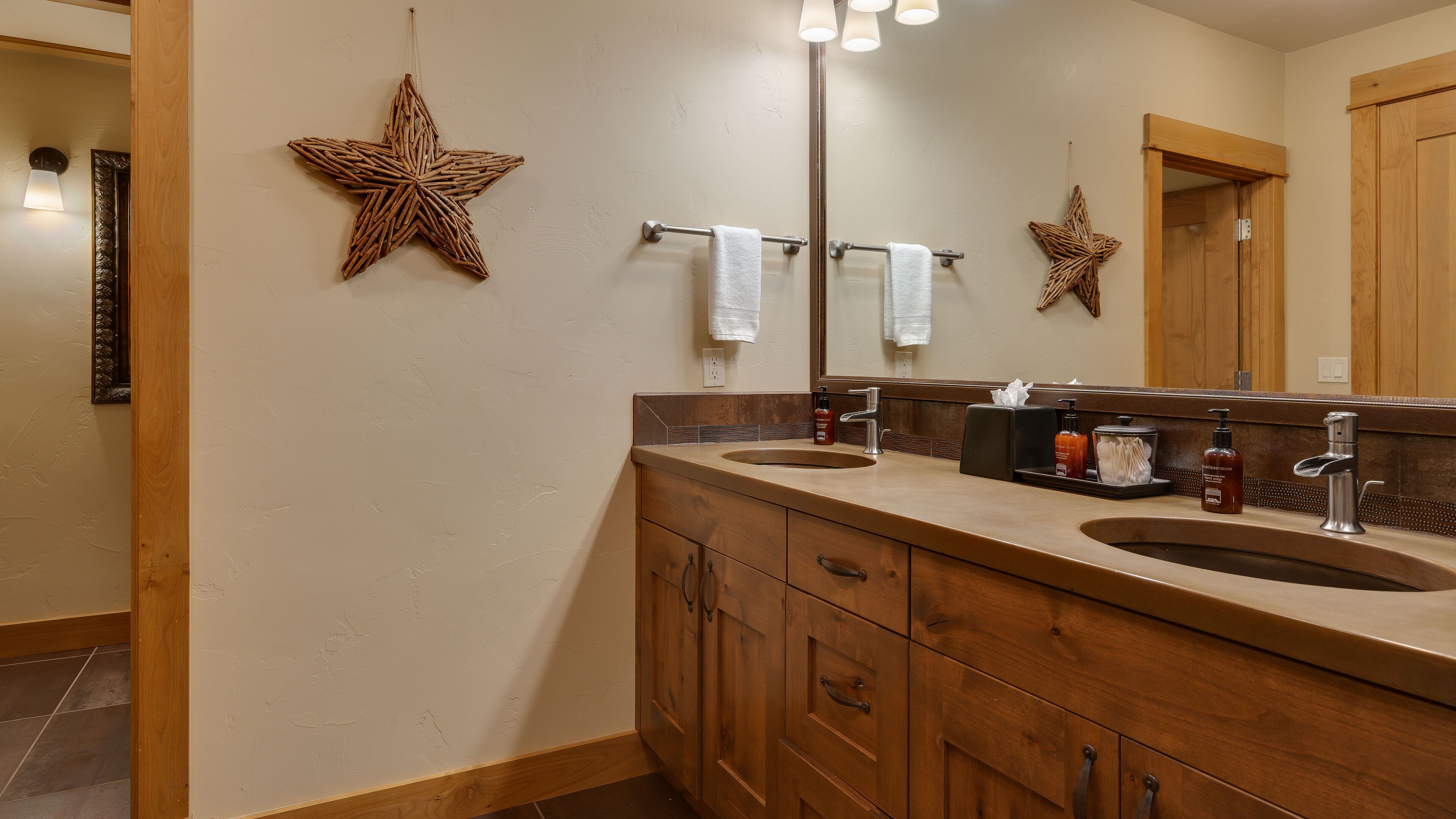 Un baño con dos lavamanos, armarios de madera, un espejo y adornos de estrellas en la pared.