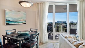 A balcony with a view of the city skyline, a dining area with a table and chairs, and a sofa. - Paradise at the Palms * Summer Specials! Book Now! 2 King Beds~2 Full Baths! (Destin)